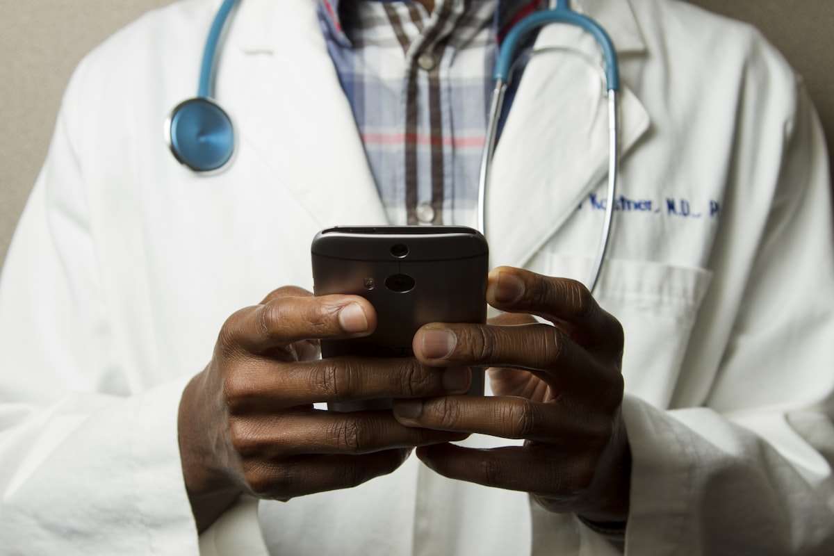 A clinician in white coat reviewing patient data on a tablet